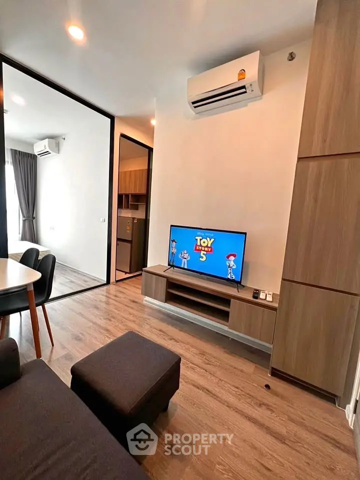 Modern living room with air conditioning and TV, featuring sleek wooden flooring and contemporary furniture.