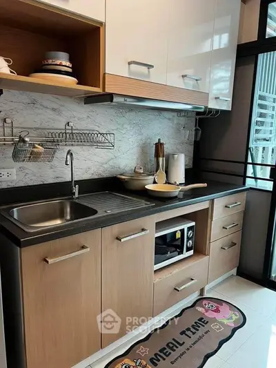 Modern kitchen with sleek cabinets, marble backsplash, and built-in oven, perfect for culinary enthusiasts.