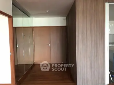 Spacious hallway with wooden flooring and mirrored closet doors in modern apartment.