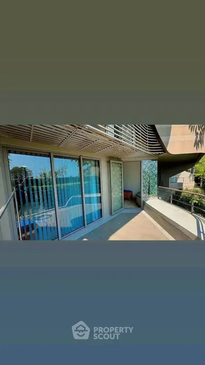 Spacious balcony with modern railing and pool view in luxury apartment