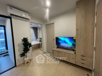 Modern living room with wooden furniture and flat-screen TV, adjacent to a cozy bedroom.