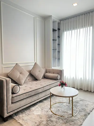 Elegant living room with plush sofa and chic round coffee table by large window.
