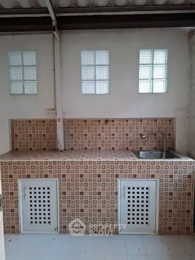 Charming kitchen with tiled backsplash and built-in sink, perfect for modern living.