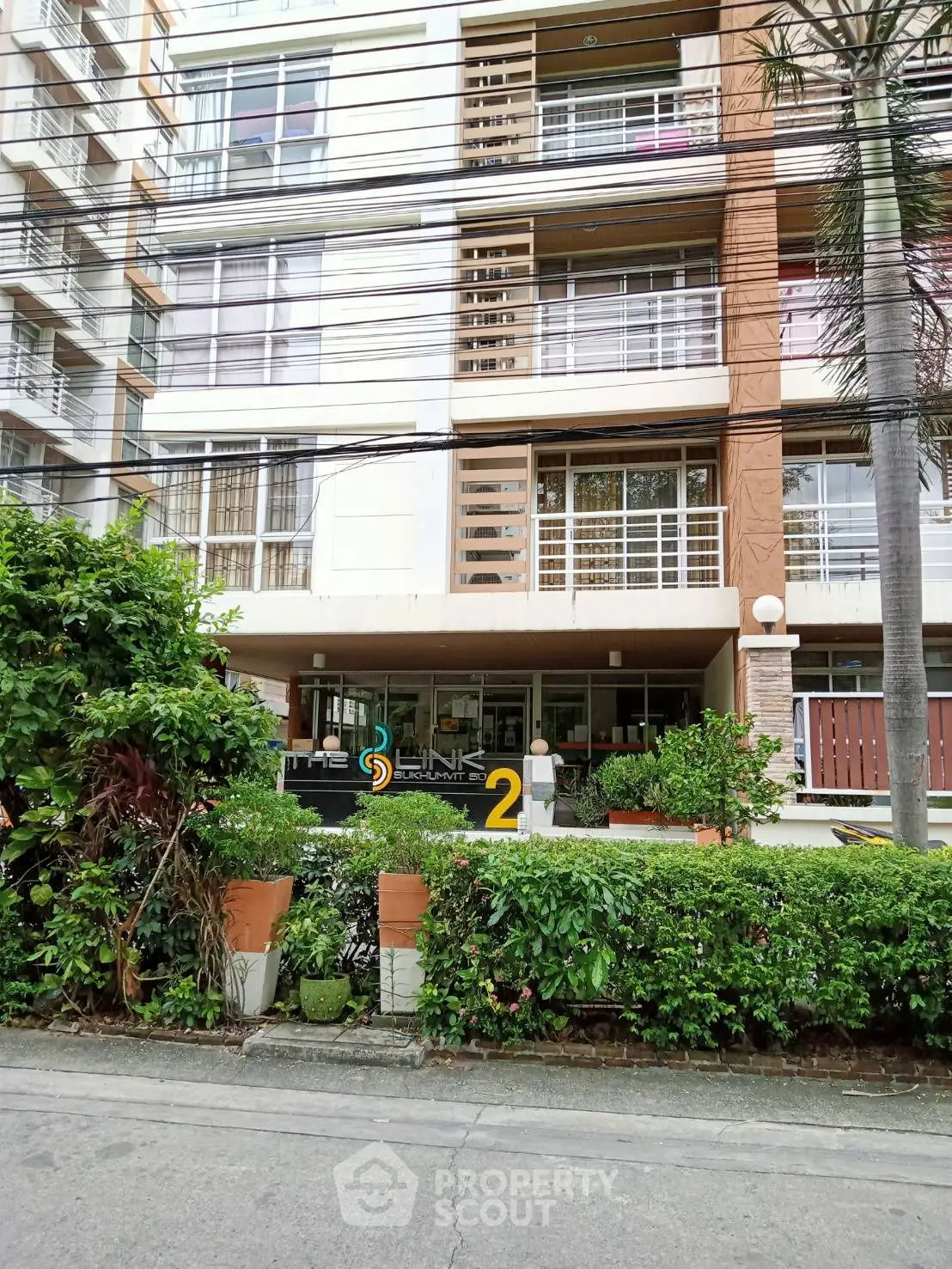 Modern apartment building exterior with lush greenery and stylish facade.