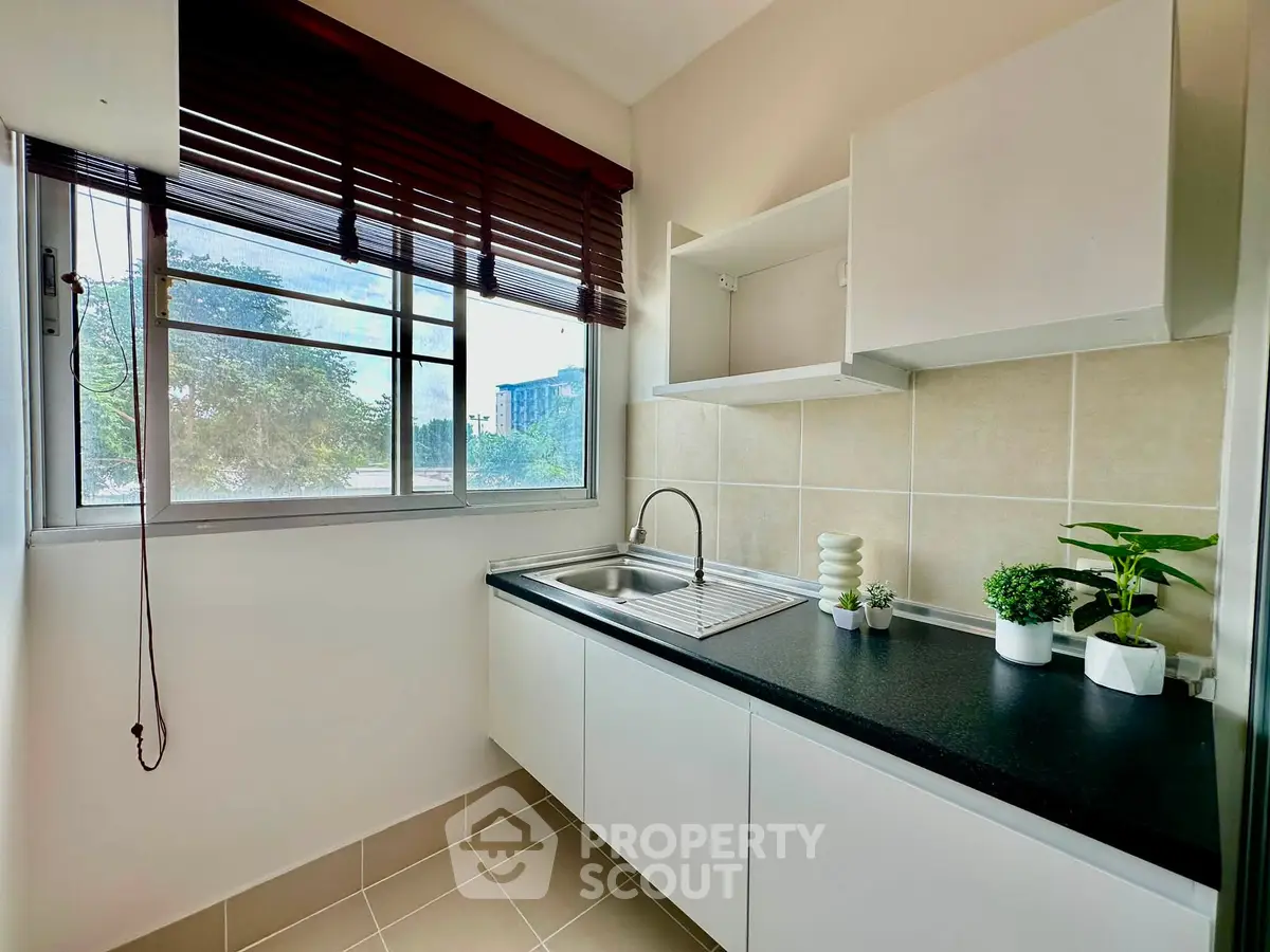 Modern kitchen with sleek cabinetry and large window offering natural light.