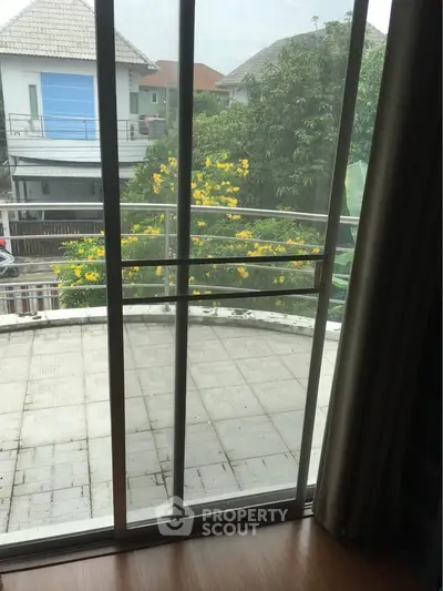 Spacious balcony with sliding glass door and garden view in modern home.