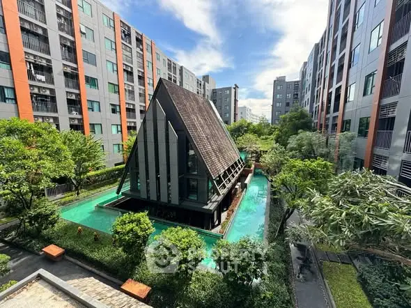 Modern apartment complex with unique triangular structure and lush garden view.