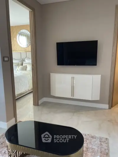 Modern living area with wall-mounted TV and elegant decor near bedroom entrance.