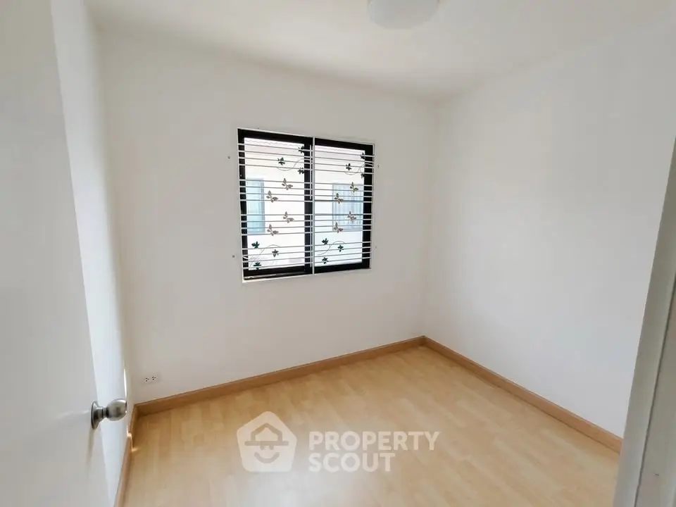 Bright empty room with wooden flooring and window, perfect for customization.