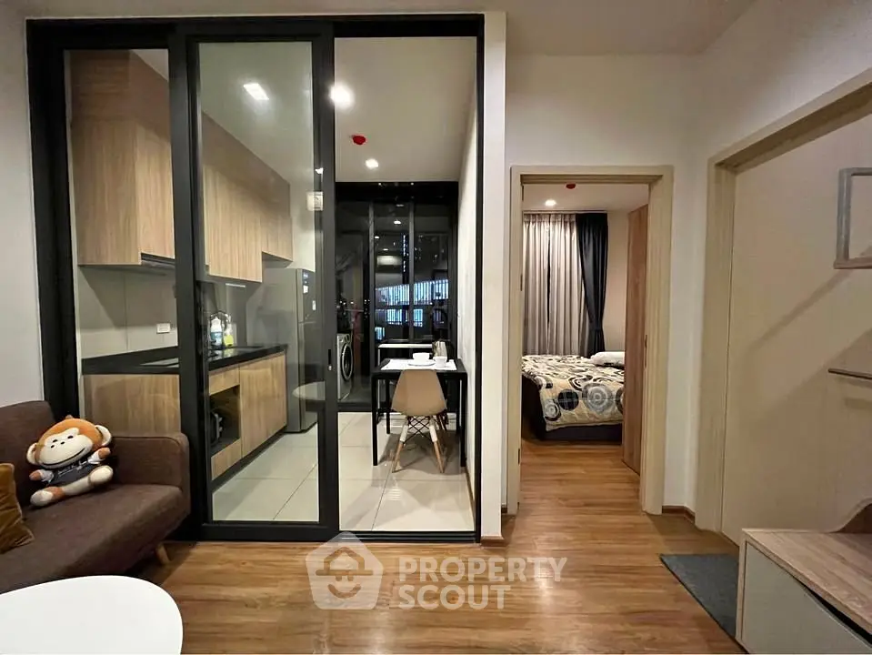 Modern apartment interior with open kitchen and cozy living area, featuring stylish decor and wooden flooring.