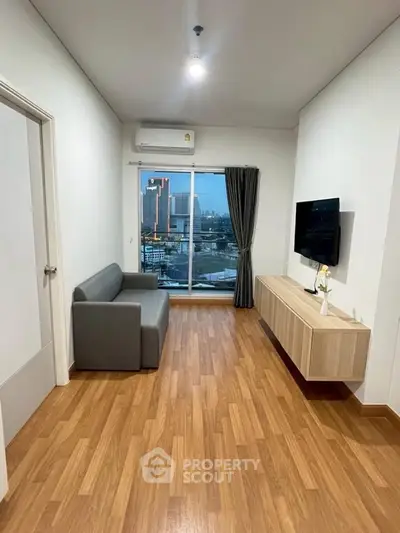 Modern living room with wooden flooring, sleek furniture, and city view from large window.