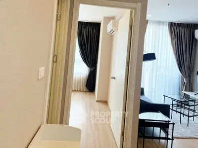 Modern apartment interior with open living room and bedroom, featuring sleek furniture and large windows.