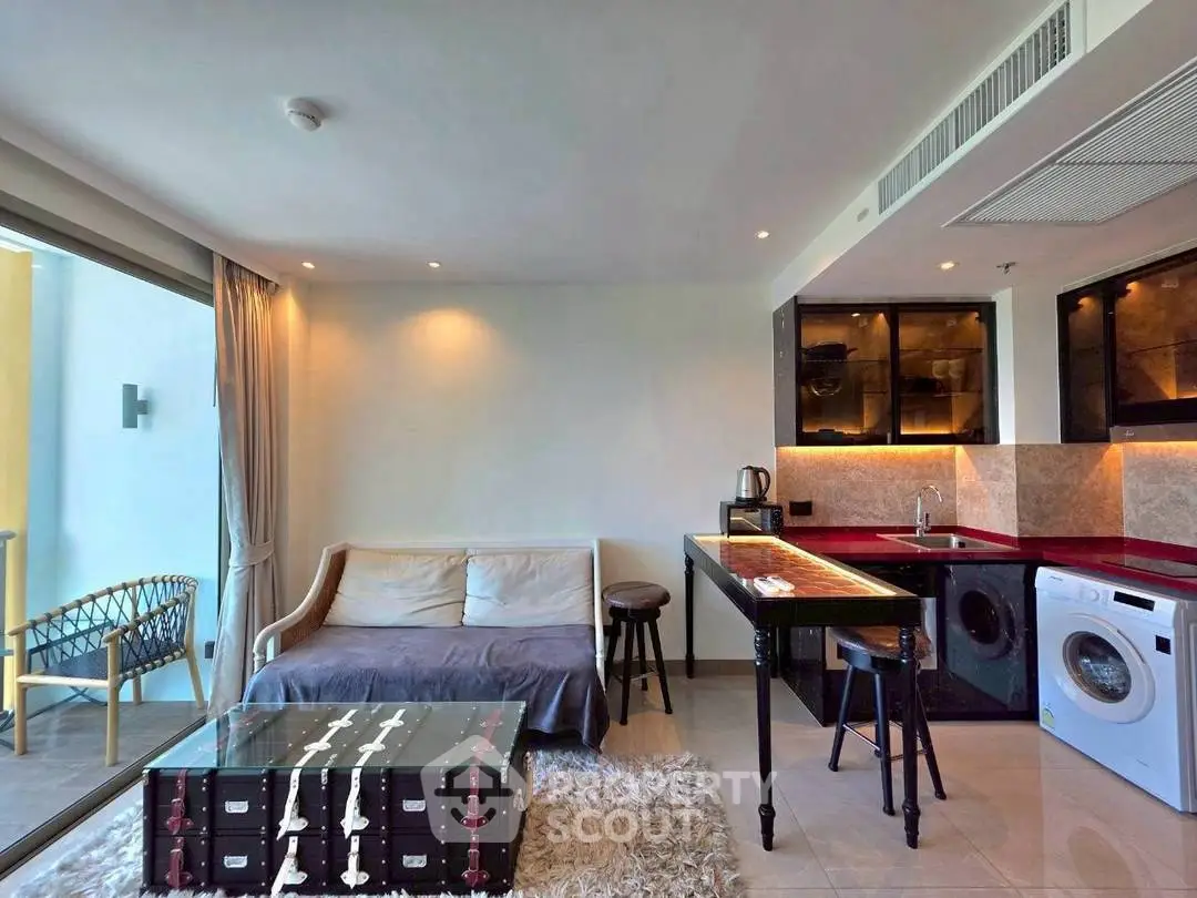 Modern living room with open kitchen, featuring stylish furniture and balcony access in a chic apartment.