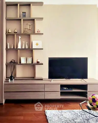 Modern living room with stylish shelving and flat-screen TV on wooden cabinet.