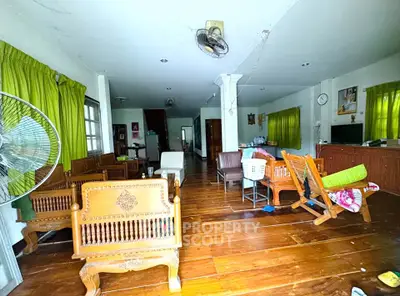 Spacious living room with wooden flooring and traditional furniture, featuring green curtains and ample natural light.