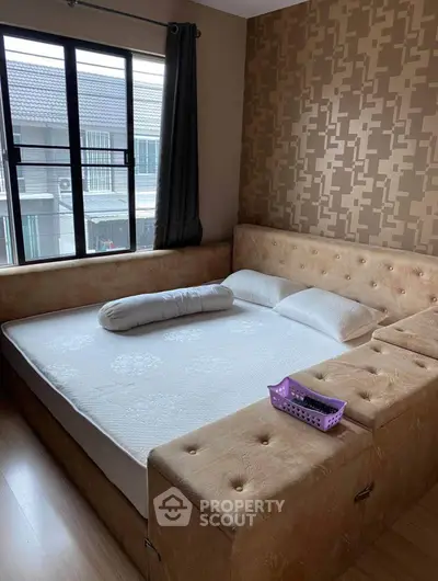Cozy bedroom with modern decor and large window offering natural light.