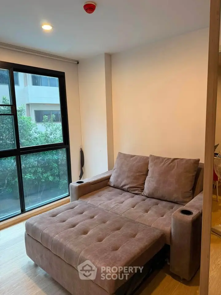 Cozy living room with modern sofa and large window offering natural light.