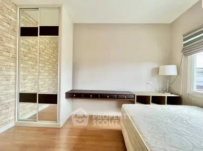 Modern bedroom with wooden floor, built-in wardrobe, and natural light.