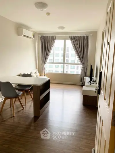 Modern living room with large window, wooden flooring, and stylish furniture in a bright apartment.