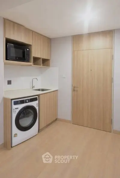 Modern compact kitchen with built-in microwave and washing machine in sleek wooden cabinetry.
