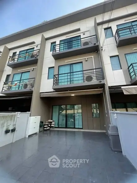 Modern multi-story townhouse with balconies and spacious driveway
