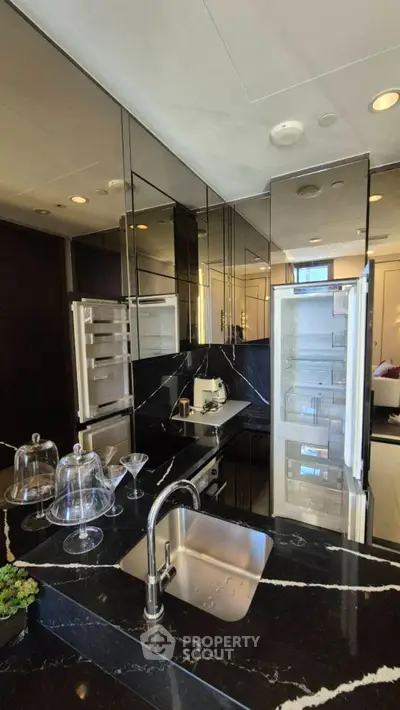 Luxurious modern kitchen with sleek black marble countertops and mirrored cabinets