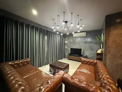 Luxurious living room with leather sofas and modern chandelier lighting.