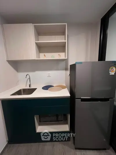 Modern compact kitchen with sleek cabinetry and stainless steel fridge