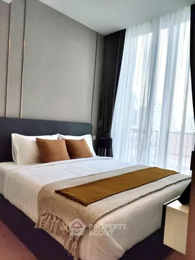 Modern bedroom with large window and stylish decor in urban apartment.