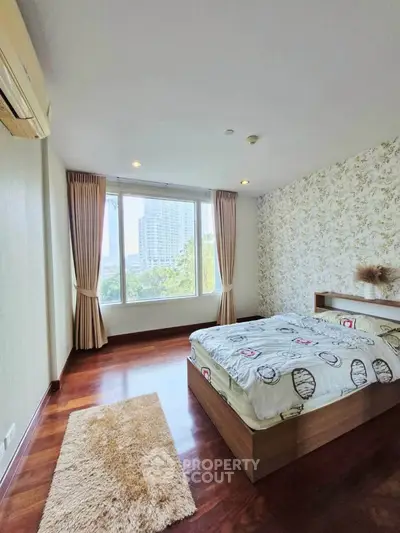 Spacious bedroom with large window and elegant decor in modern apartment