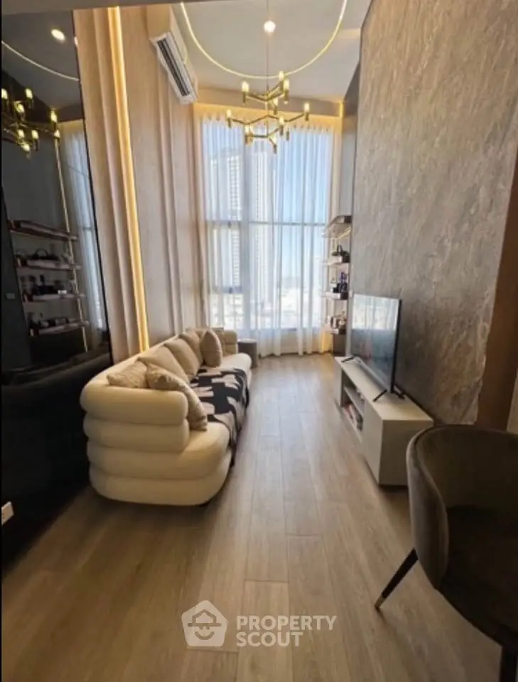 Luxurious modern living room with high ceilings, elegant chandelier, and floor-to-ceiling windows offering city views.