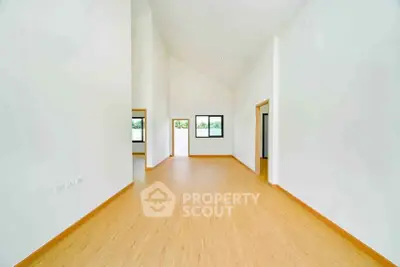 Spacious modern living room with high ceilings and wooden flooring, perfect for contemporary living.