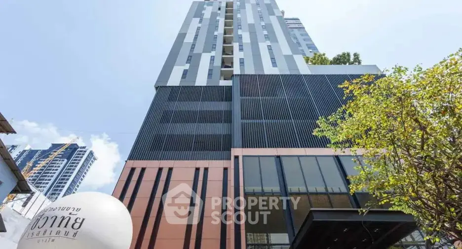 Modern high-rise building exterior with sleek design and urban surroundings.