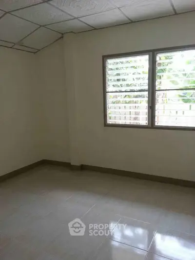 Spacious empty room with large window and tiled floor, perfect for customization.