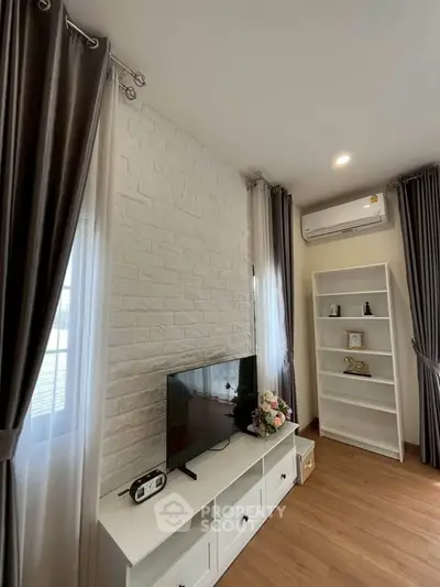 Charming living room with modern decor, featuring a TV unit, elegant curtains, and air conditioning.