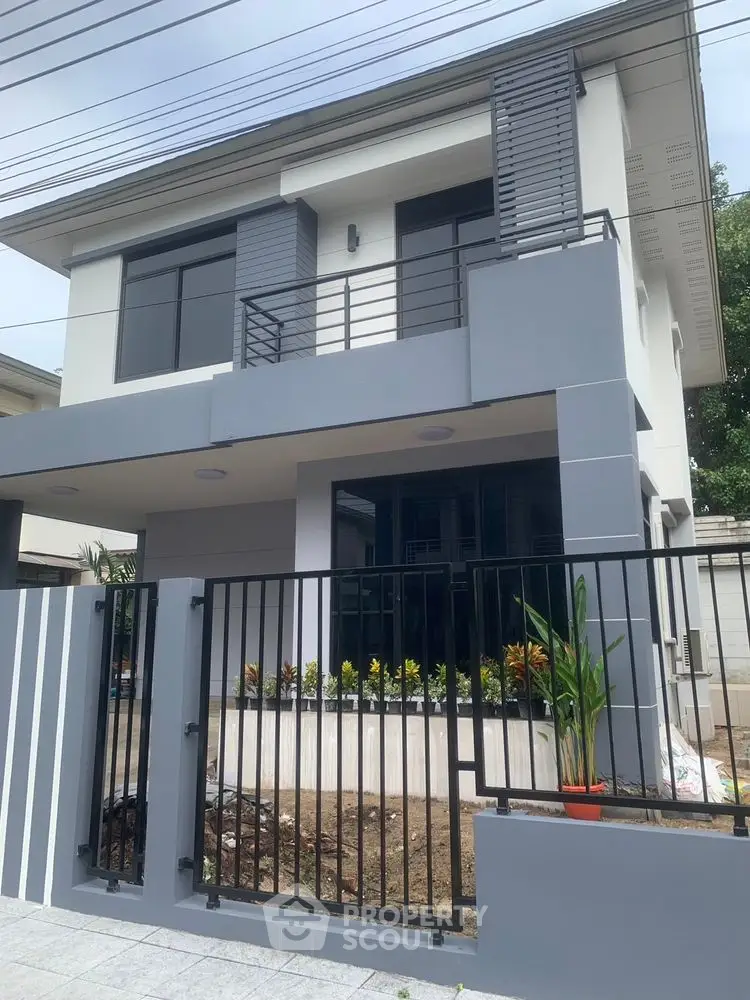 Modern two-story house with sleek design and landscaped front yard, featuring large windows and a secure gate.