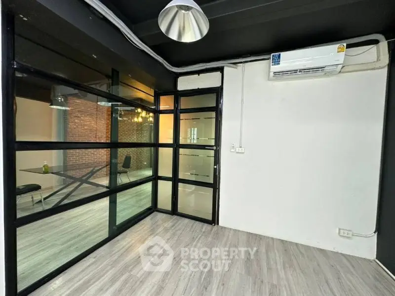Modern office space with glass partitions and air conditioning in a sleek, industrial-style building.