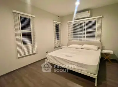 Spacious bedroom with modern design and air conditioning, featuring large windows and elegant blinds.