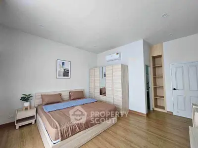 Spacious modern bedroom with wooden flooring and stylish furniture
