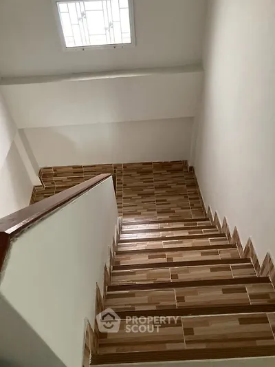 Modern staircase with wooden steps and natural light from skylight