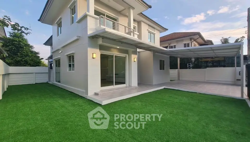 Modern two-story house with spacious lawn and covered parking area in a serene neighborhood.