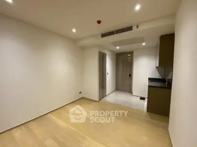 Spacious modern apartment interior with wooden flooring and sleek kitchen design.