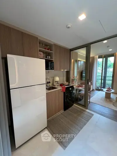 Modern kitchen with sleek appliances and open layout leading to dining area with garden view.