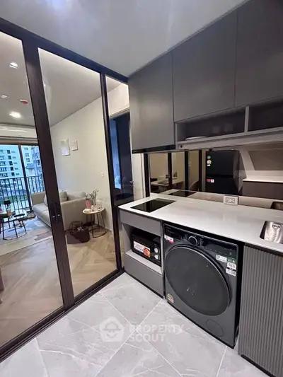 Modern kitchen with sleek appliances and open layout leading to a cozy living room and balcony view.