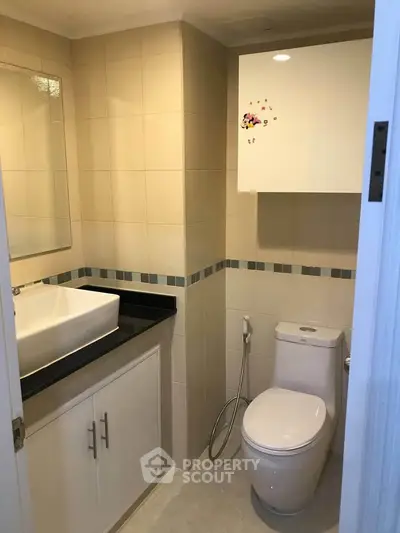 Modern bathroom with sleek fixtures and neutral tiles, featuring a stylish vanity and toilet.