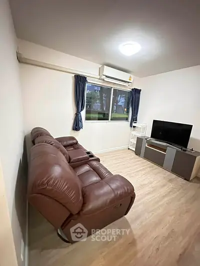 Cozy living room with leather sofa and modern TV setup, perfect for relaxation.