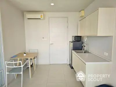 Modern compact kitchen with dining area and air conditioning in a cozy apartment.