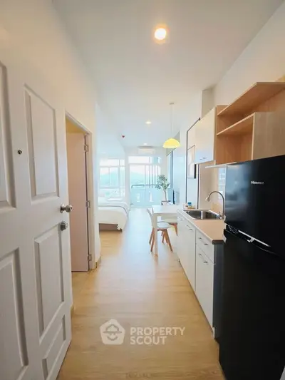 Modern open-layout kitchen with sleek appliances and bright natural light, leading to a cozy bedroom with a view.