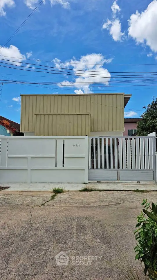 Modern minimalist house exterior with white fence and clear blue sky.