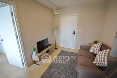 Cozy living room with modern decor and natural light, featuring a comfortable sofa and flat-screen TV.